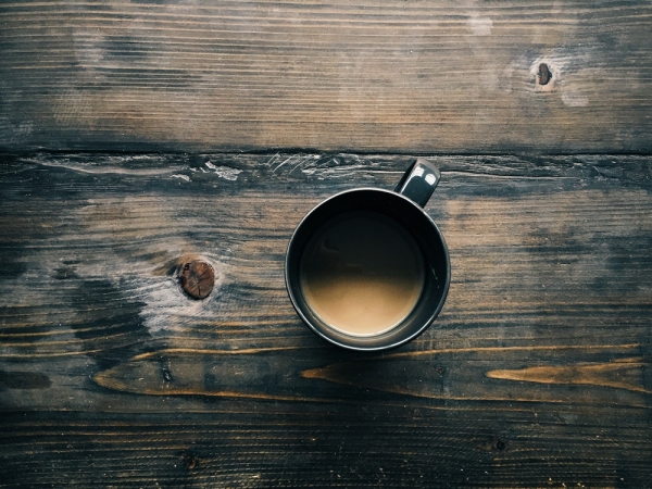 An overhead shot of a cup of coffee on a wooden surface